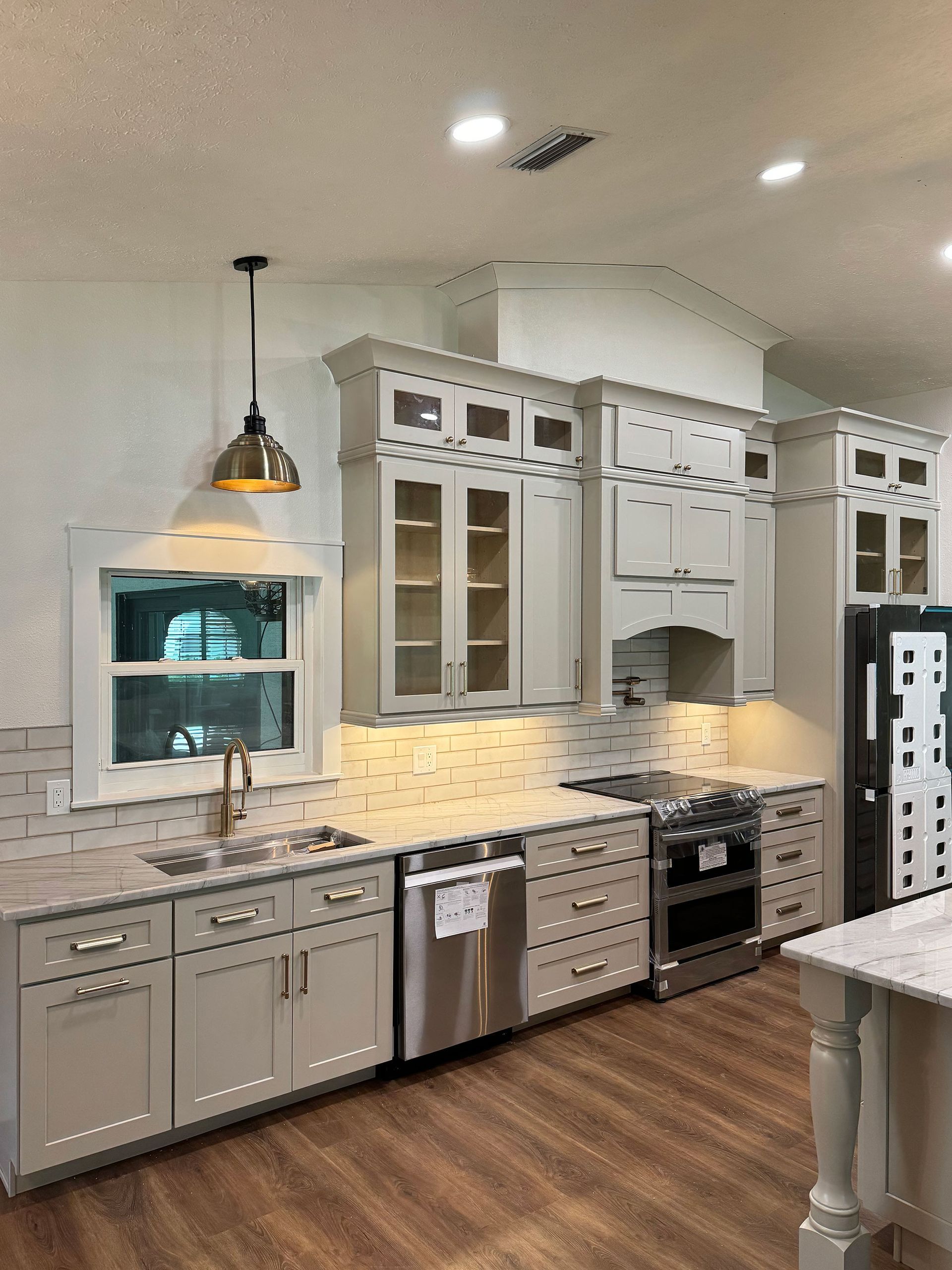Bright modern kitchen with white cabinets, stainless appliances, marble counters, and pendant lighting