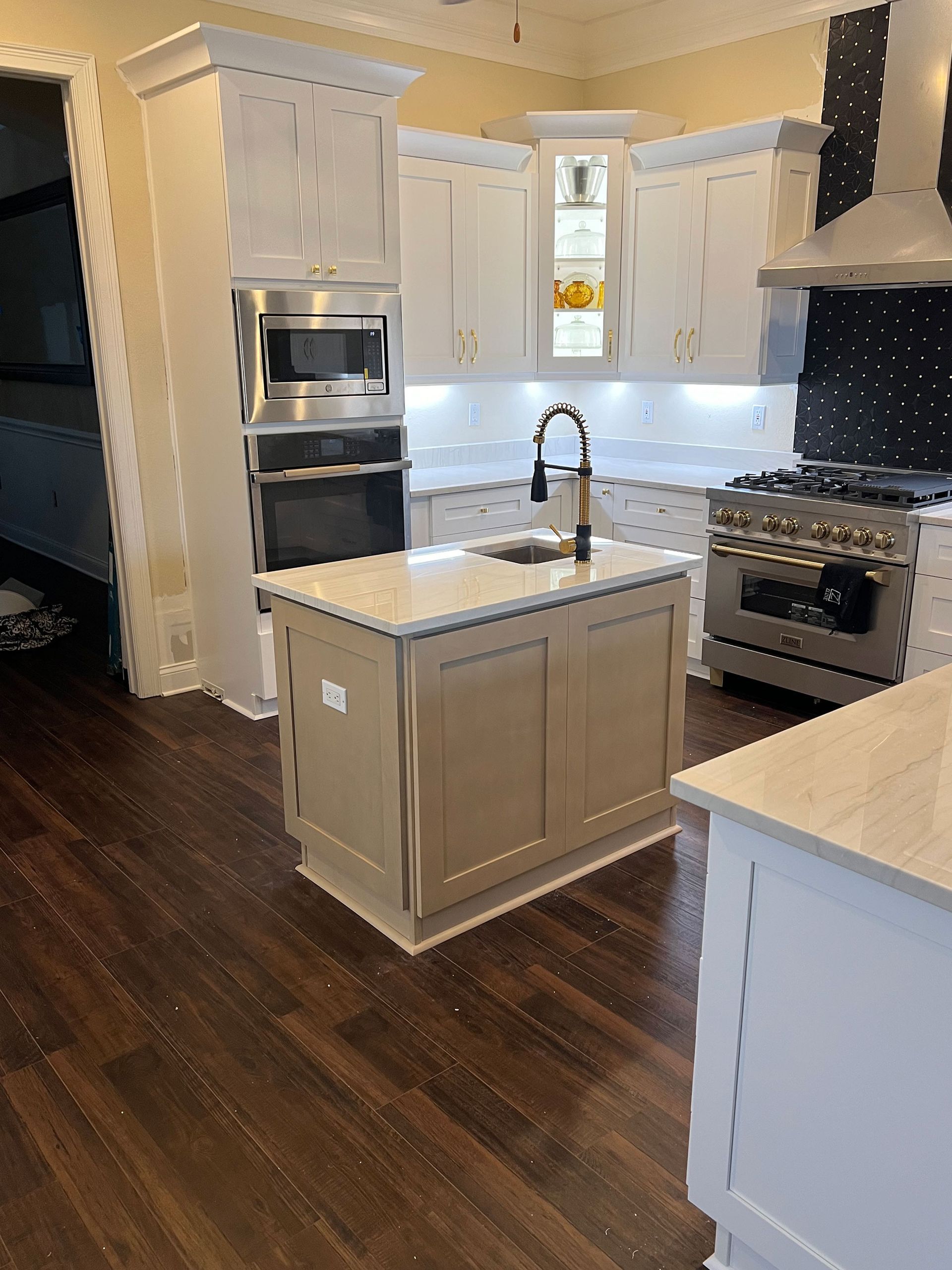 Bright modern kitchen with white cabinets, dark wood floors, center island, and stainless steel appliances