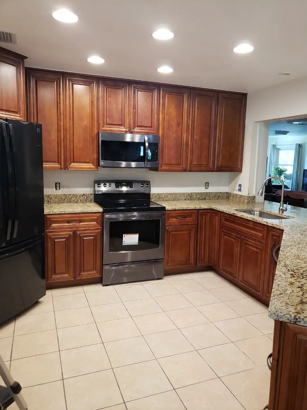Modern kitchen with dark wood cabinets, stainless steel appliances, granite countertops, and tiled floor