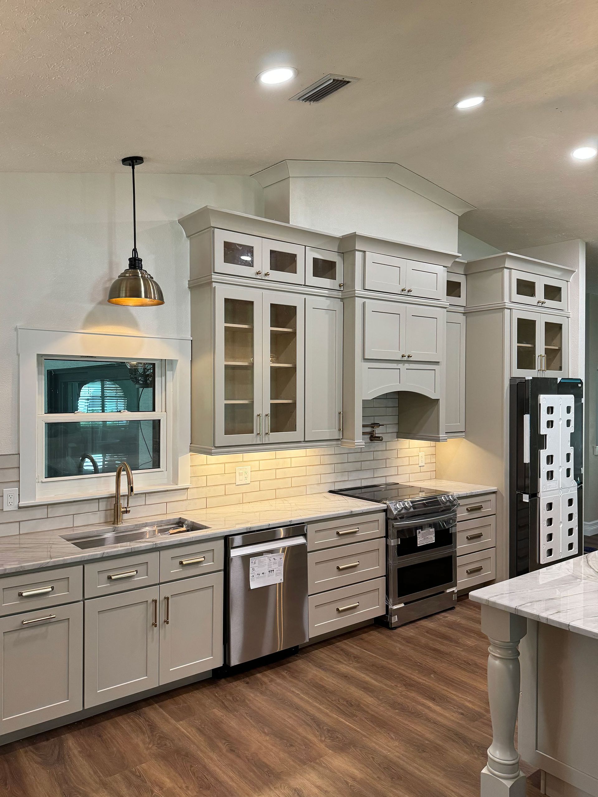 Modern kitchen with white cabinets, stainless appliances, marble backsplash, and wood floors