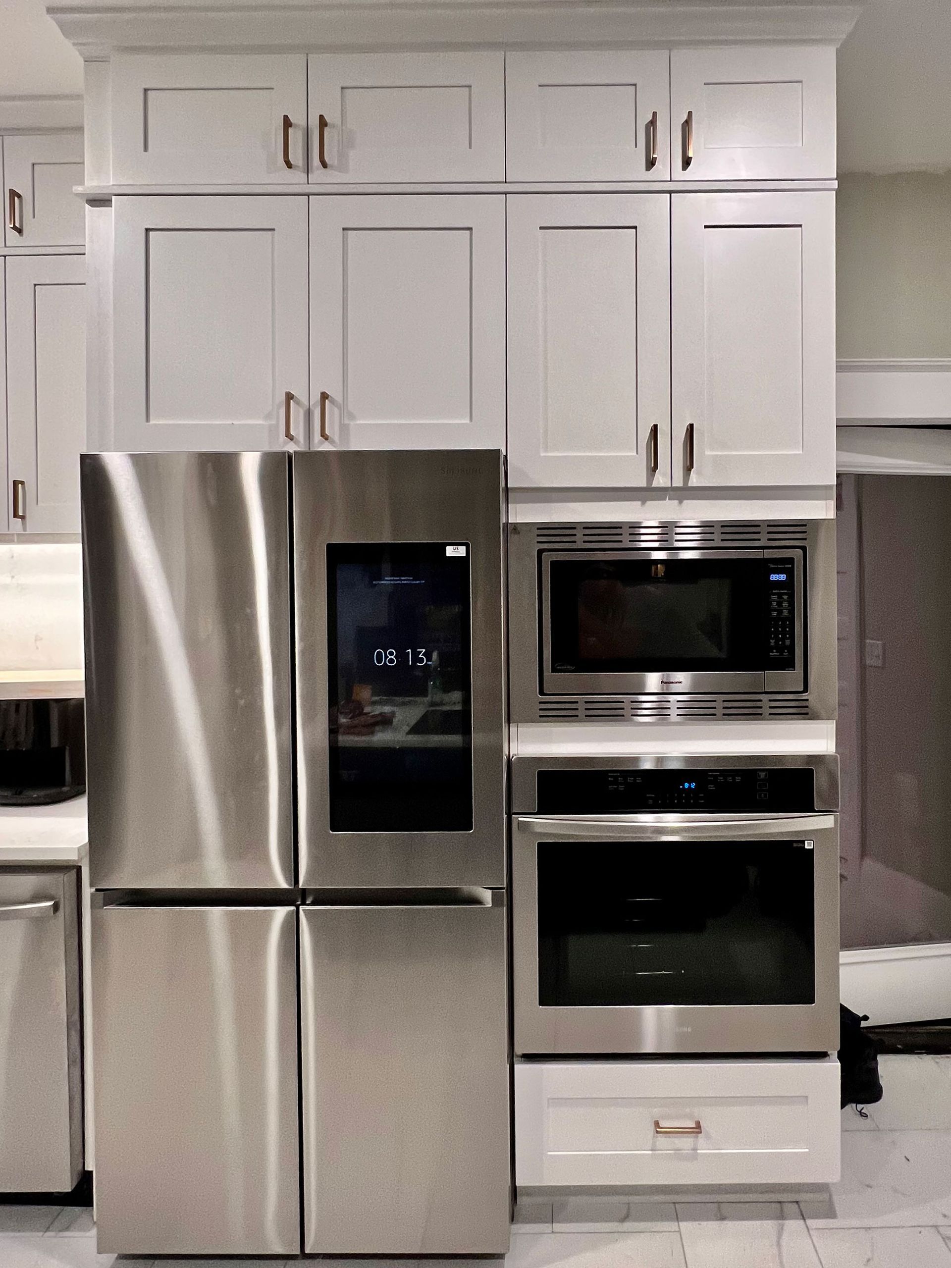 Modern kitchen with stainless steel refrigerator and built-in microwave and oven under white cabinets