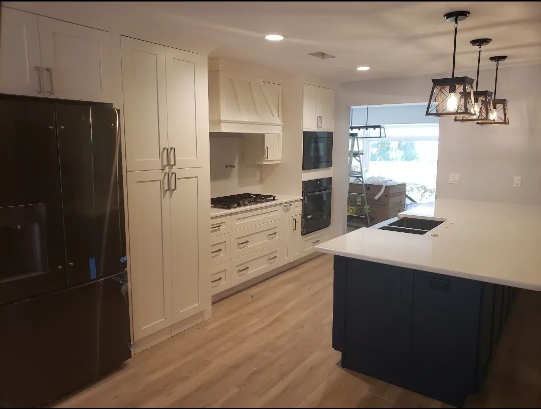 Modern kitchen with white cabinets, black refrigerator, island, and pendant lights by a bright window