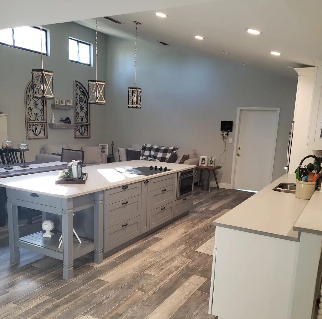 Bright modern kitchen with large island, gray cabinets, pendant lights, and wood-look flooring