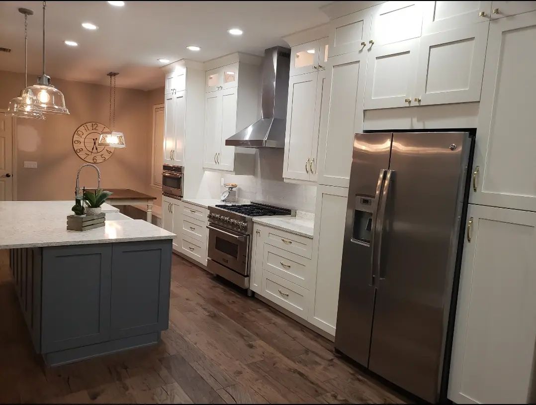 Modern kitchen with white cabinets, stainless steel appliances, gray island, and warm wood floors
