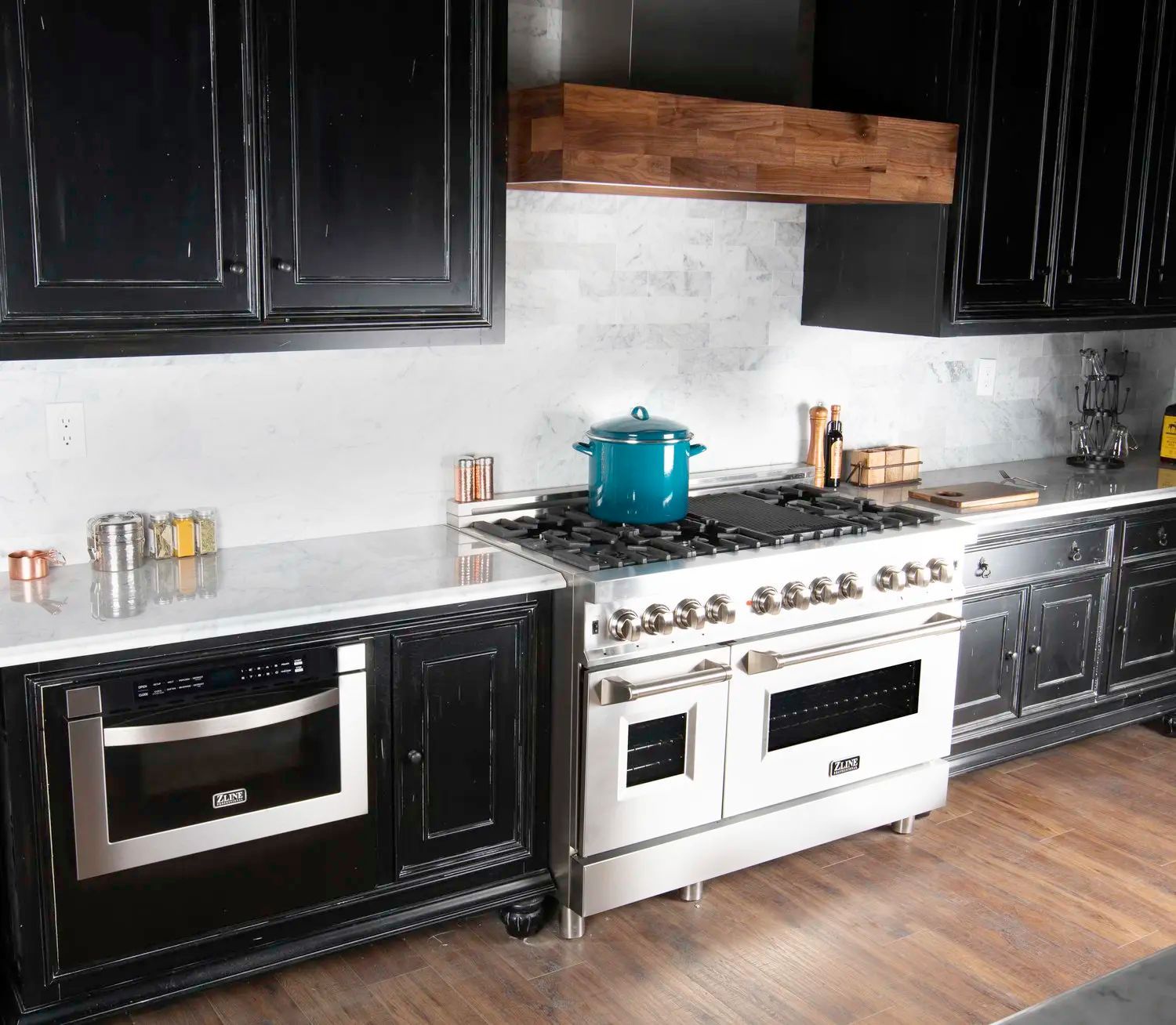 Modern kitchen with black cabinets, white range, and teal pot on the stove