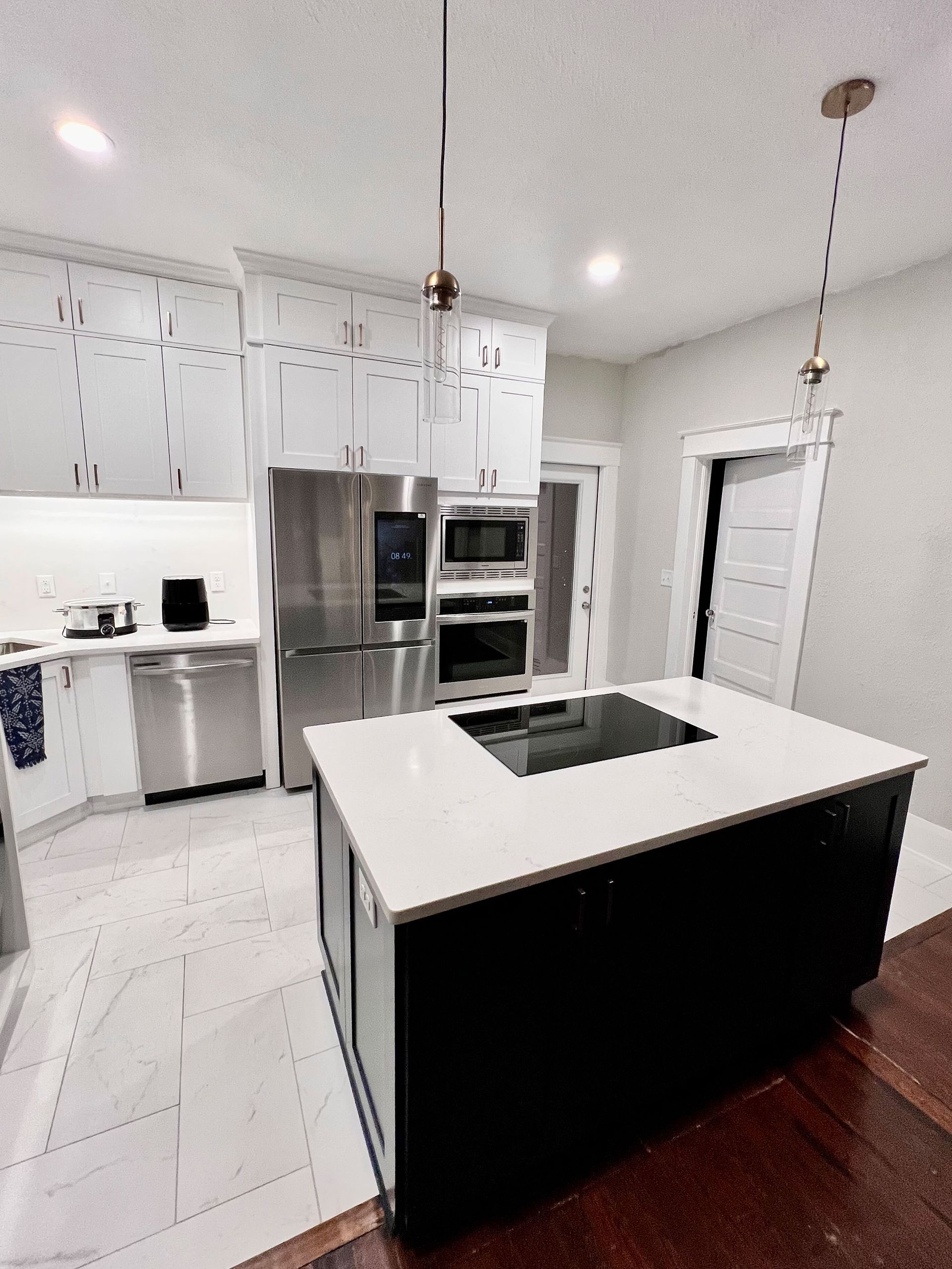 Modern white kitchen with stainless steel appliances and a black island with sink
