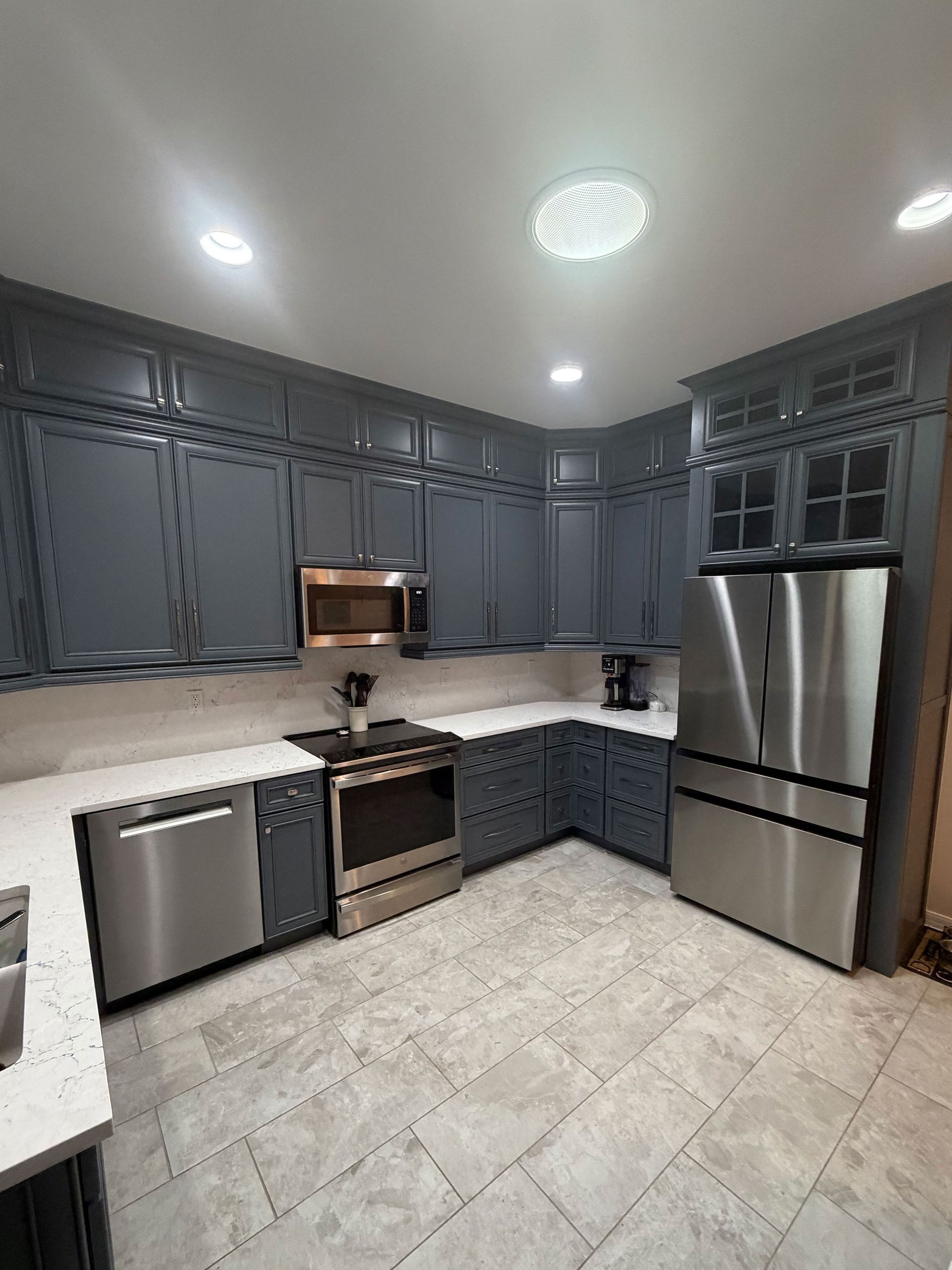 Modern kitchen with gray cabinets, stainless appliances, and tiled floor