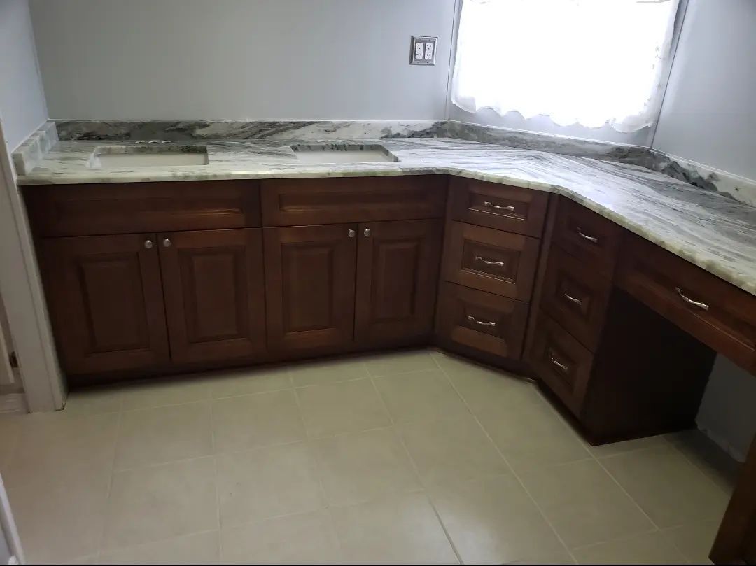 Empty kitchen with dark wood cabinets, granite countertops, and a window above the sink.