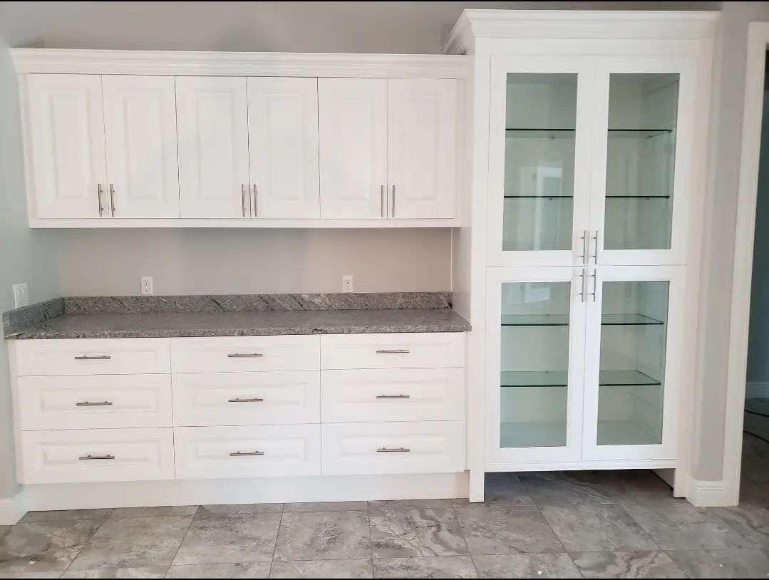 White kitchen cabinetry with granite countertop and glass-front pantry cabinets