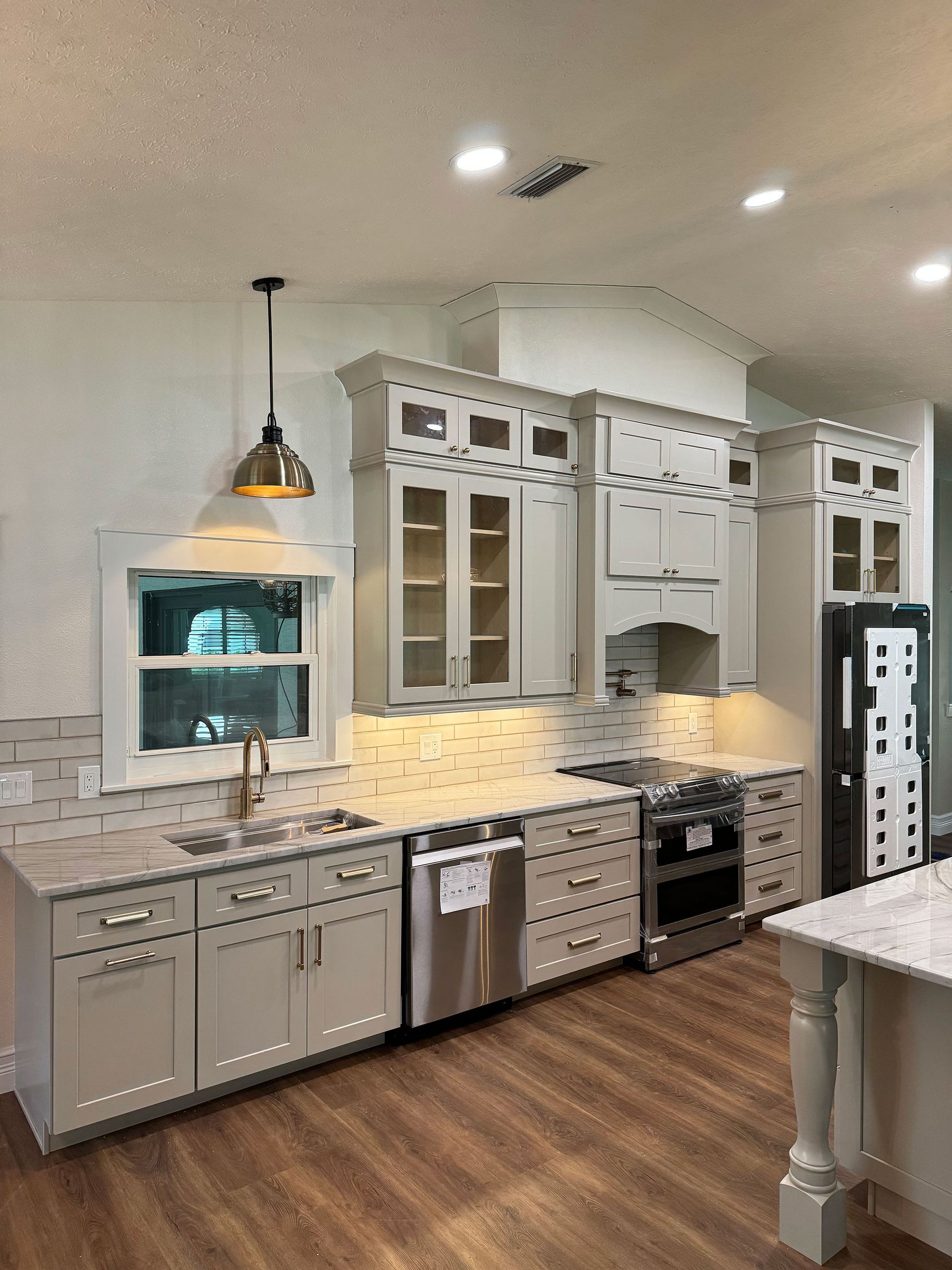Bright modern kitchen with white cabinets, stainless appliances, marble backsplash, and wood floors
