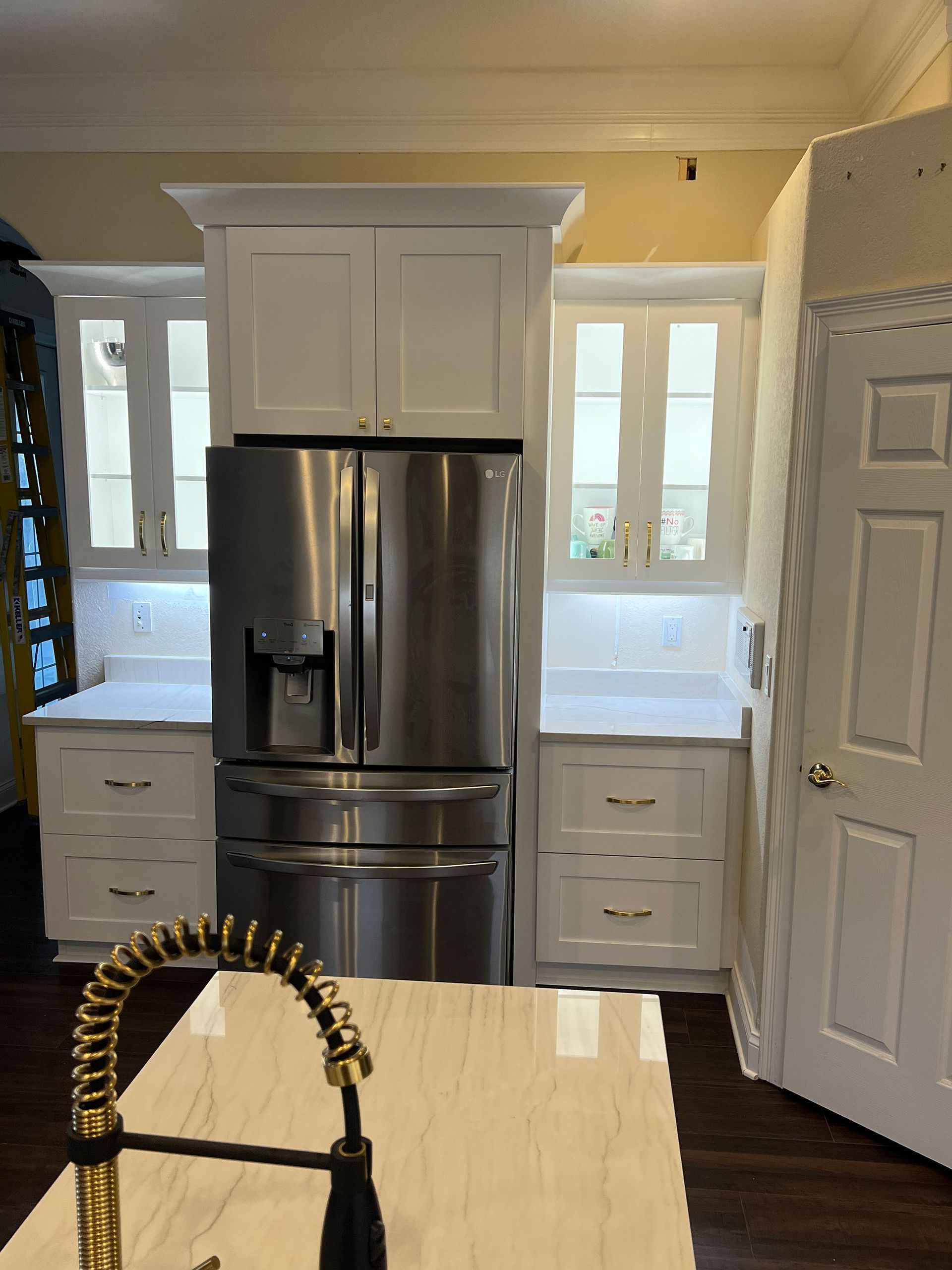 Kitchen with stainless steel fridge, white cabinets, and a cream-colored island in the foreground