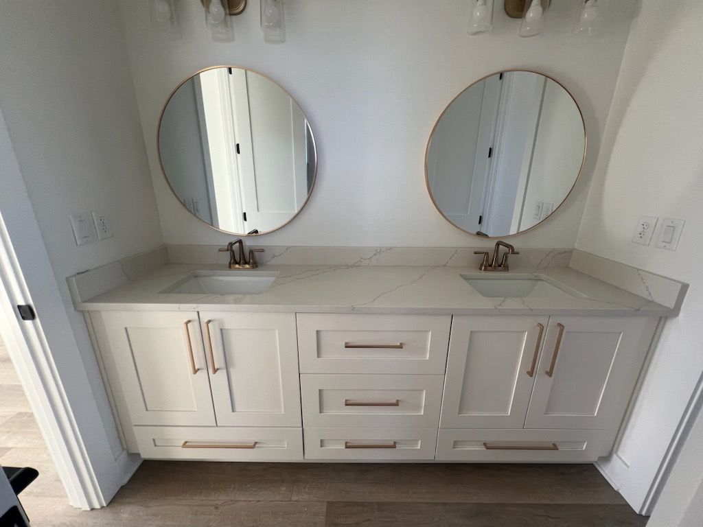 White double vanity with two round mirrors in a bright bathroom