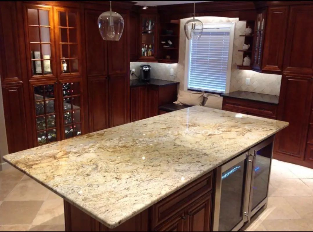 Modern kitchen with large granite island, dark wood cabinets, and window above the sink