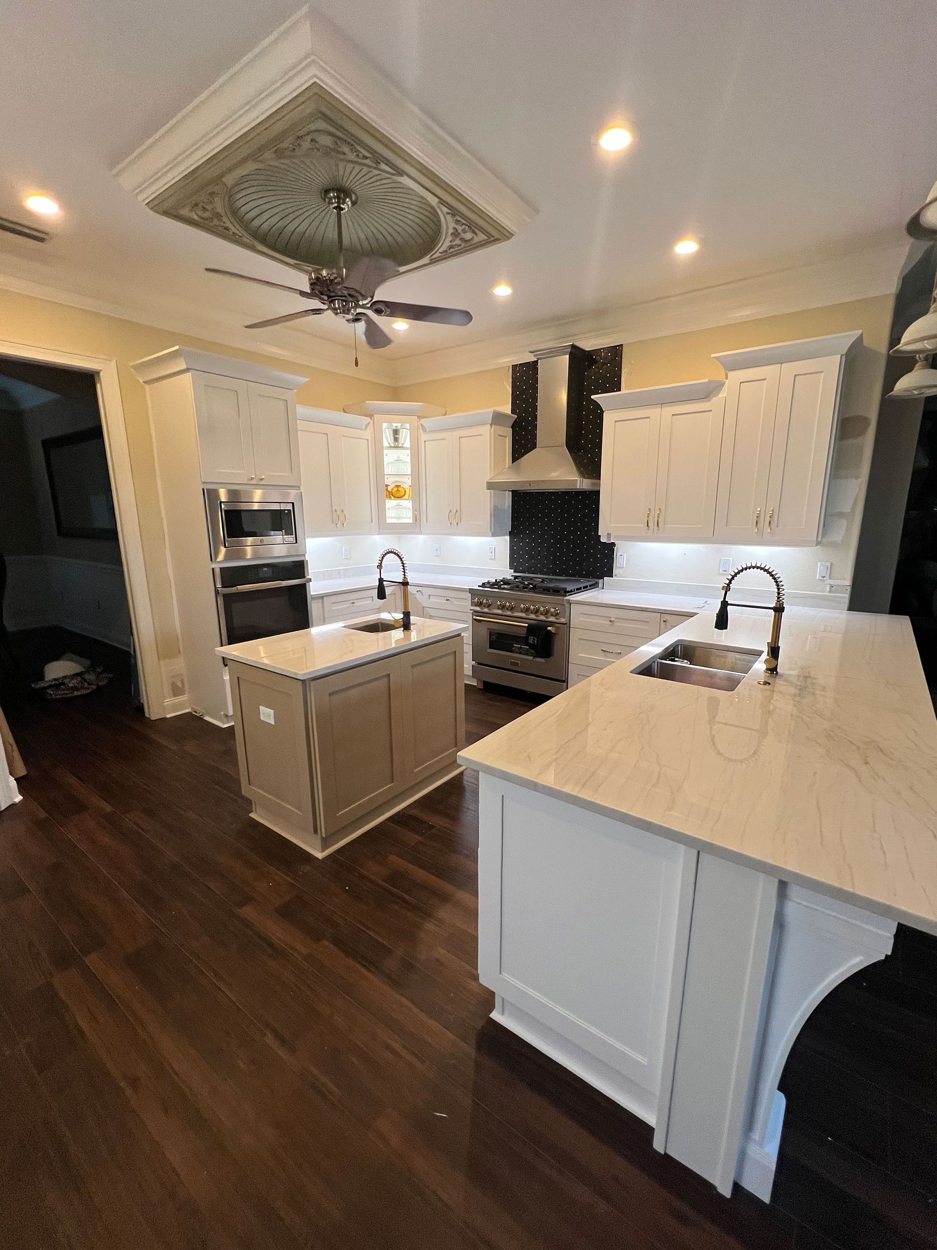 Bright modern kitchen with white cabinets, island, dark wood floors, and decorative ceiling detail