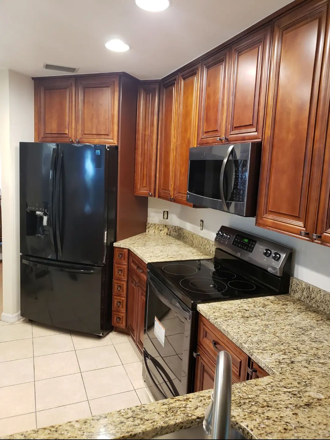 Modern kitchen with black appliances, wood cabinets, and speckled granite countertops