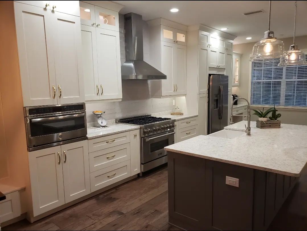 Bright modern kitchen with white cabinets, stainless appliances, and a large island under pendant lights.