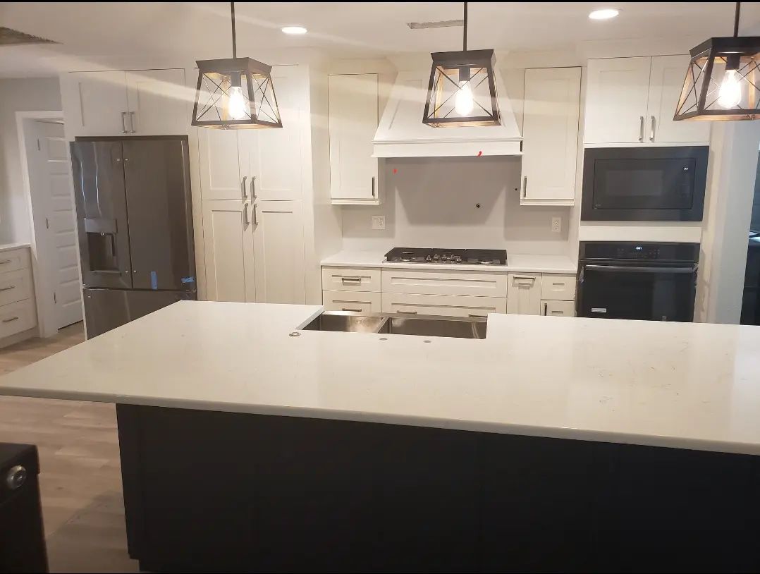 Modern kitchen with white cabinets, black appliances, and a large island under pendant lights