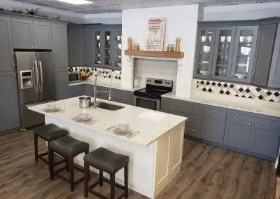 Modern gray kitchen with white island, stainless appliances, and two dark stools