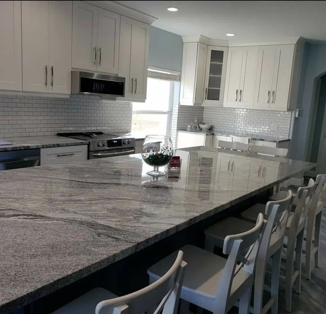 Modern kitchen with white cabinets, gray marble island, and barstools by the counter