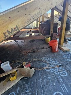 A man is standing in the attic of a house under construction