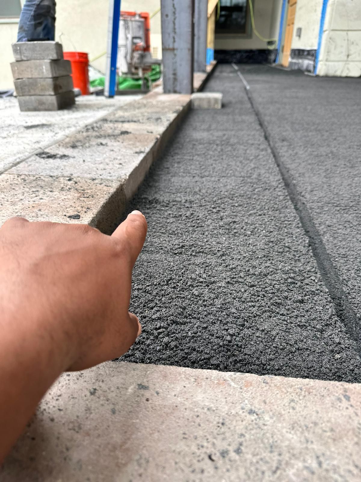 A person is pointing at a piece of asphalt on a sidewalk
