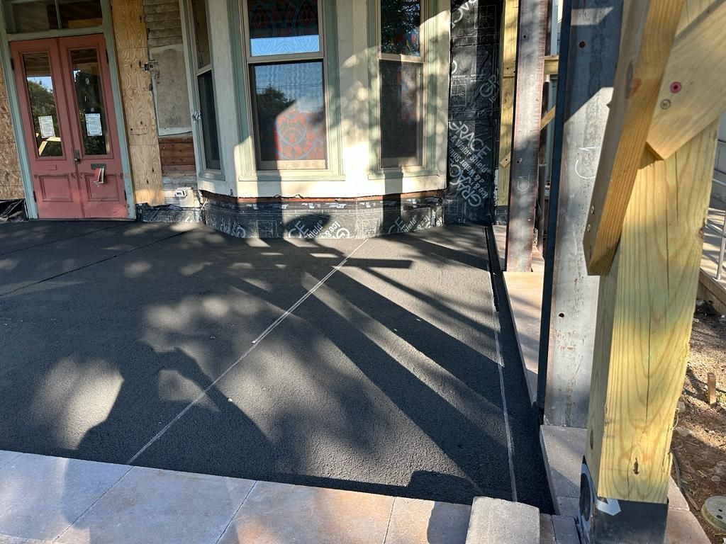 A shadow of a tree is cast on the sidewalk in front of a house