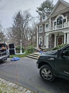 A black truck is parked in front of a large house