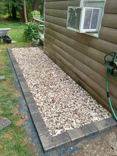 A sidewalk with gravel and bricks is being built in front of a house