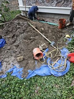 A man is digging in the dirt in a yard