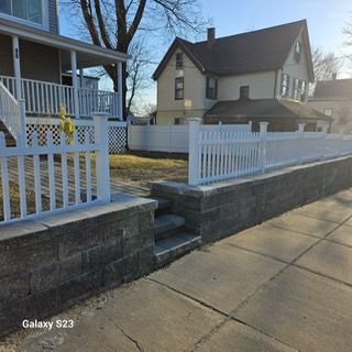 A galaxy s23 is sitting on a sidewalk next to a white fence