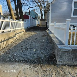A white fence surrounds a gravel path leading to a house