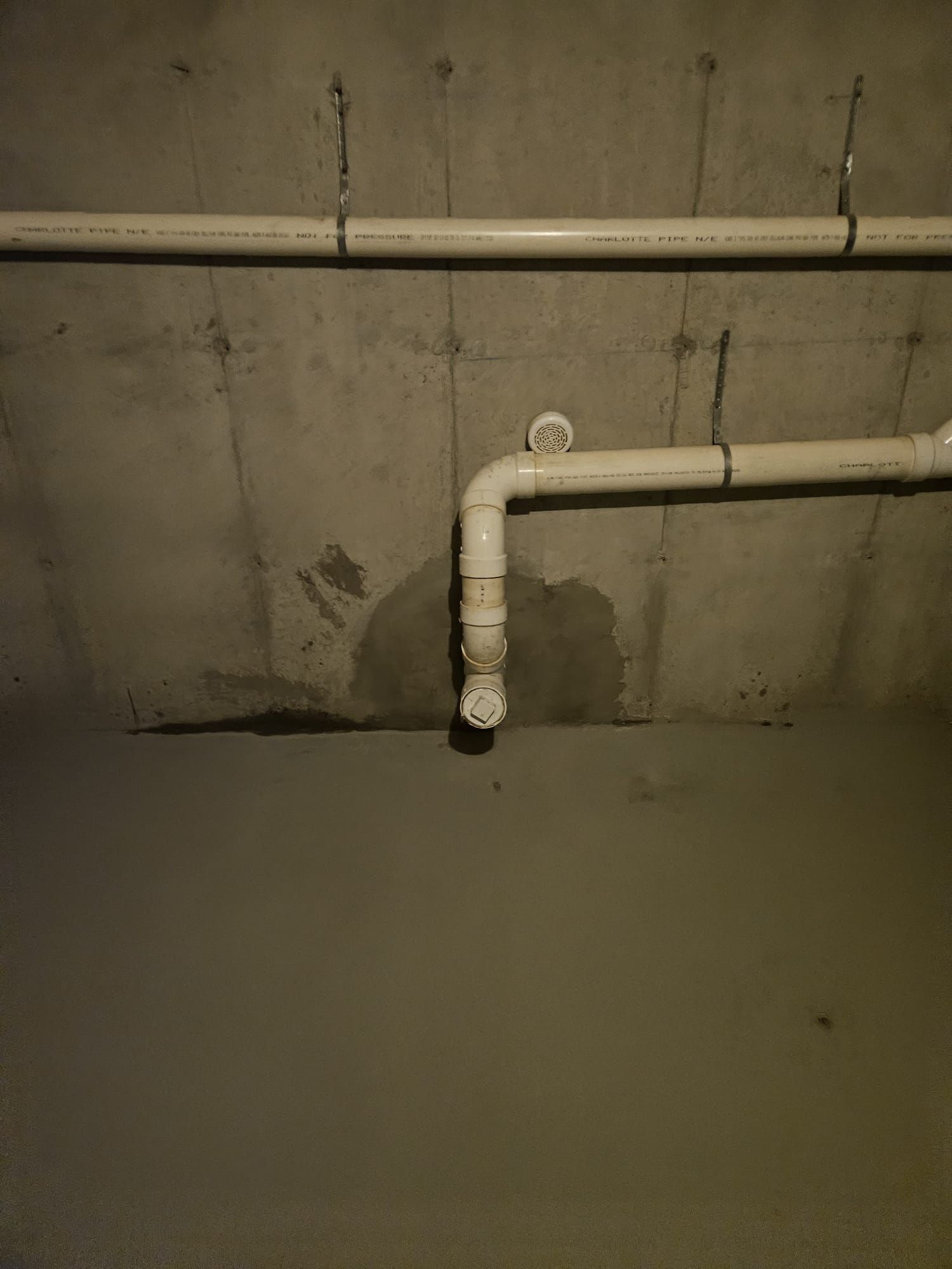 A bunch of pipes are connected to a concrete wall in a basement