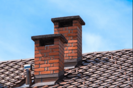 Two brick chimneys on top of a tiled roof.