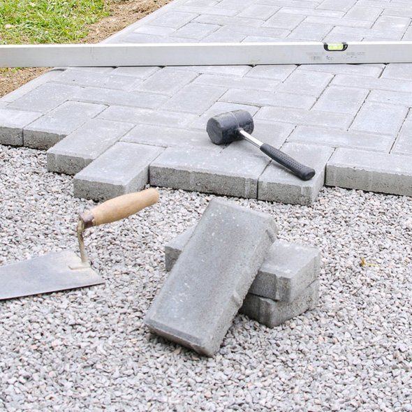 A brick walkway is being built with a hammer and trowel