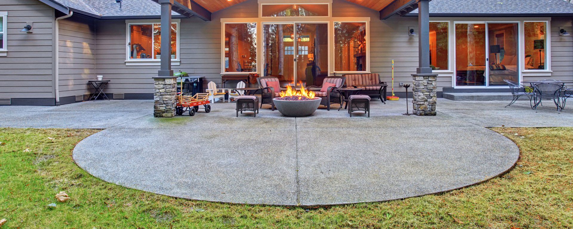 A fire pit is in the middle of a patio in front of a house