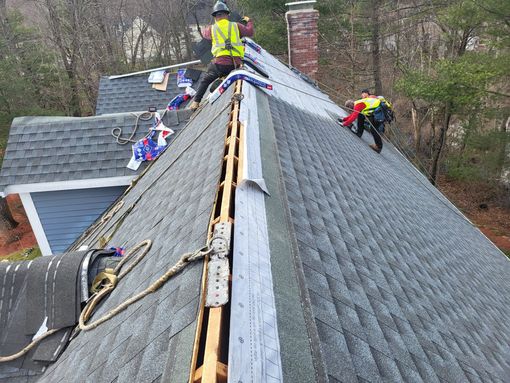 A group of people are working on the roof of a house.