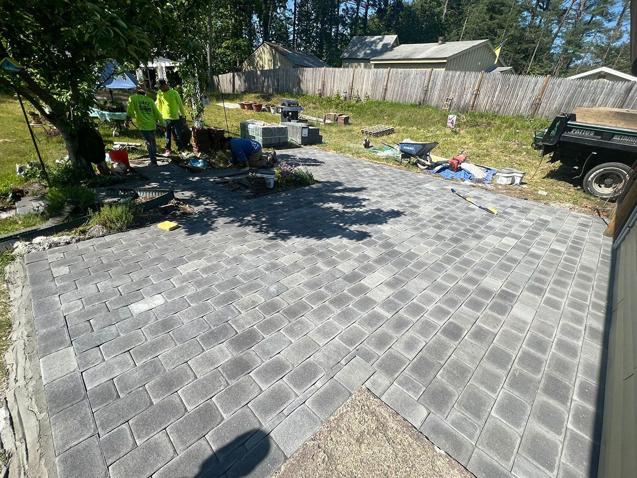 A group of people are working on a patio in a backyard
