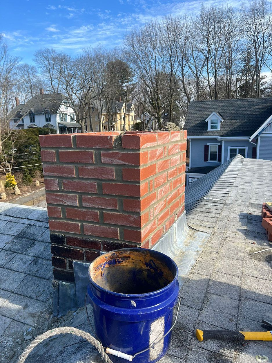 A blue bucket is sitting on top of a roof next to a brick chimney