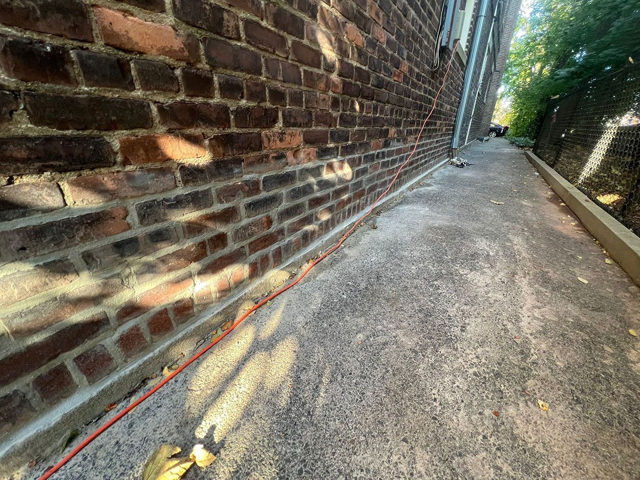 A brick wall with a concrete sidewalk
