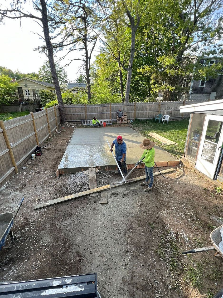 A group of man working on a concrete slab in a backyard
