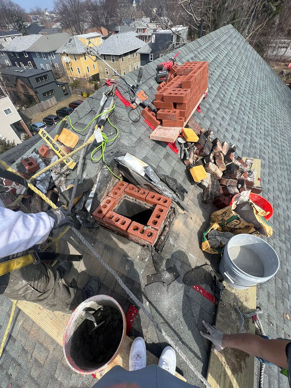 Men working on a chimney on the roof of a house