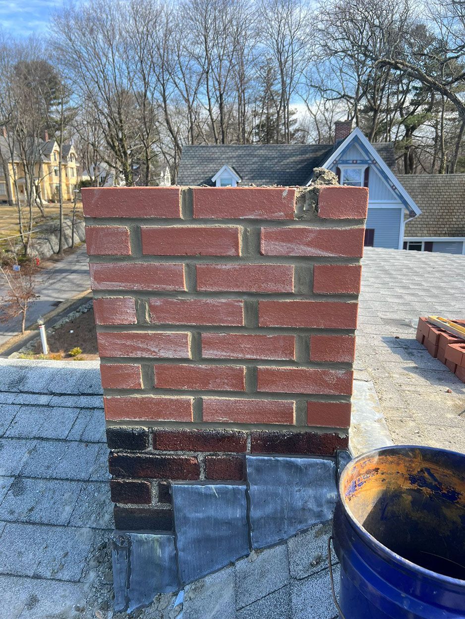 A brick chimney is being built on top of a roof
