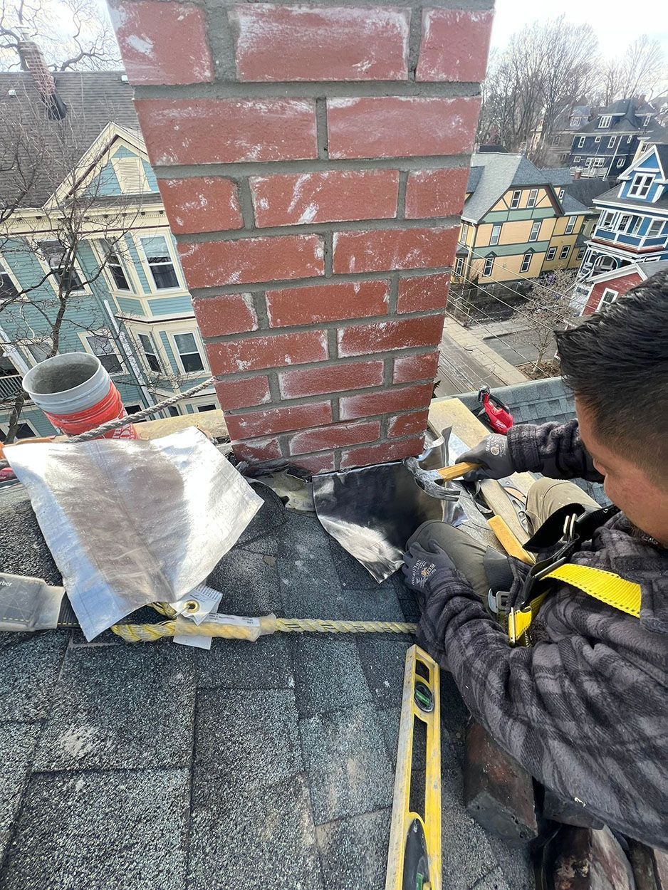 A man is working on a brick chimney on a roof
