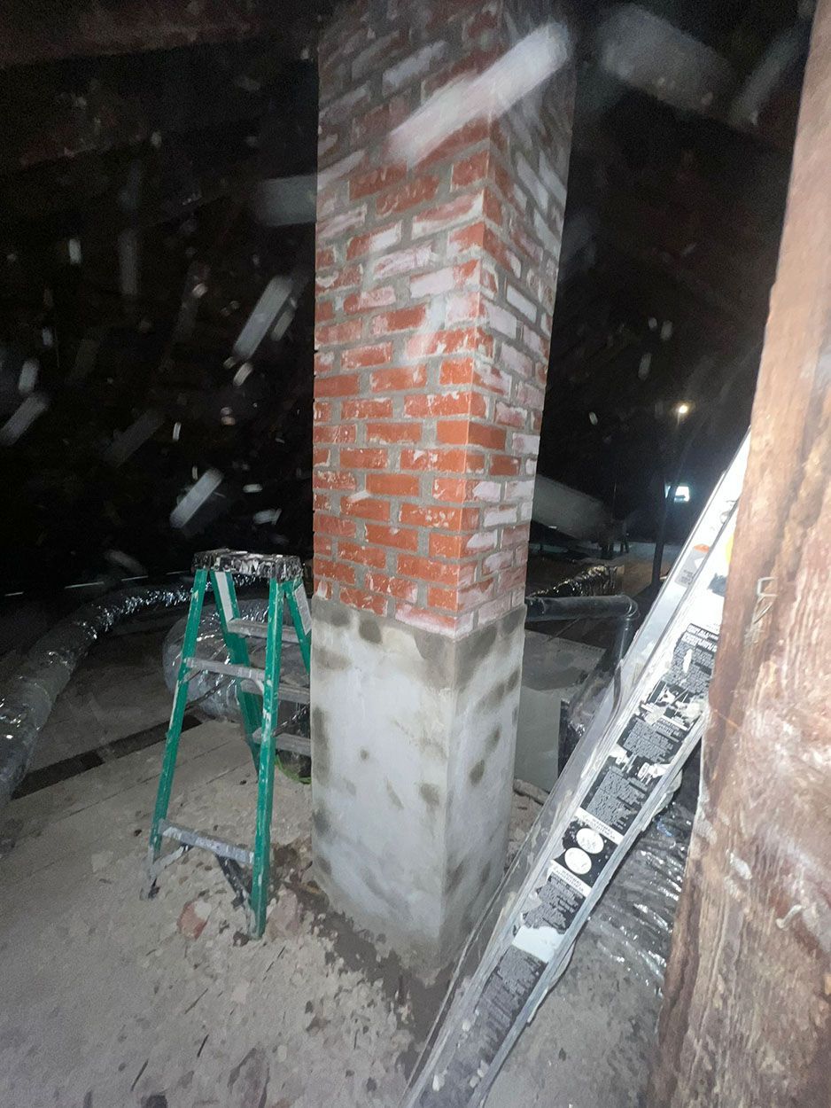 A ladder is sitting next to a brick chimney in a room