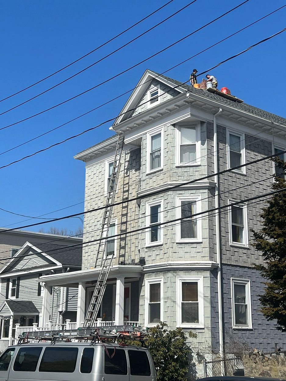 Two men are working on the roof of a huge house