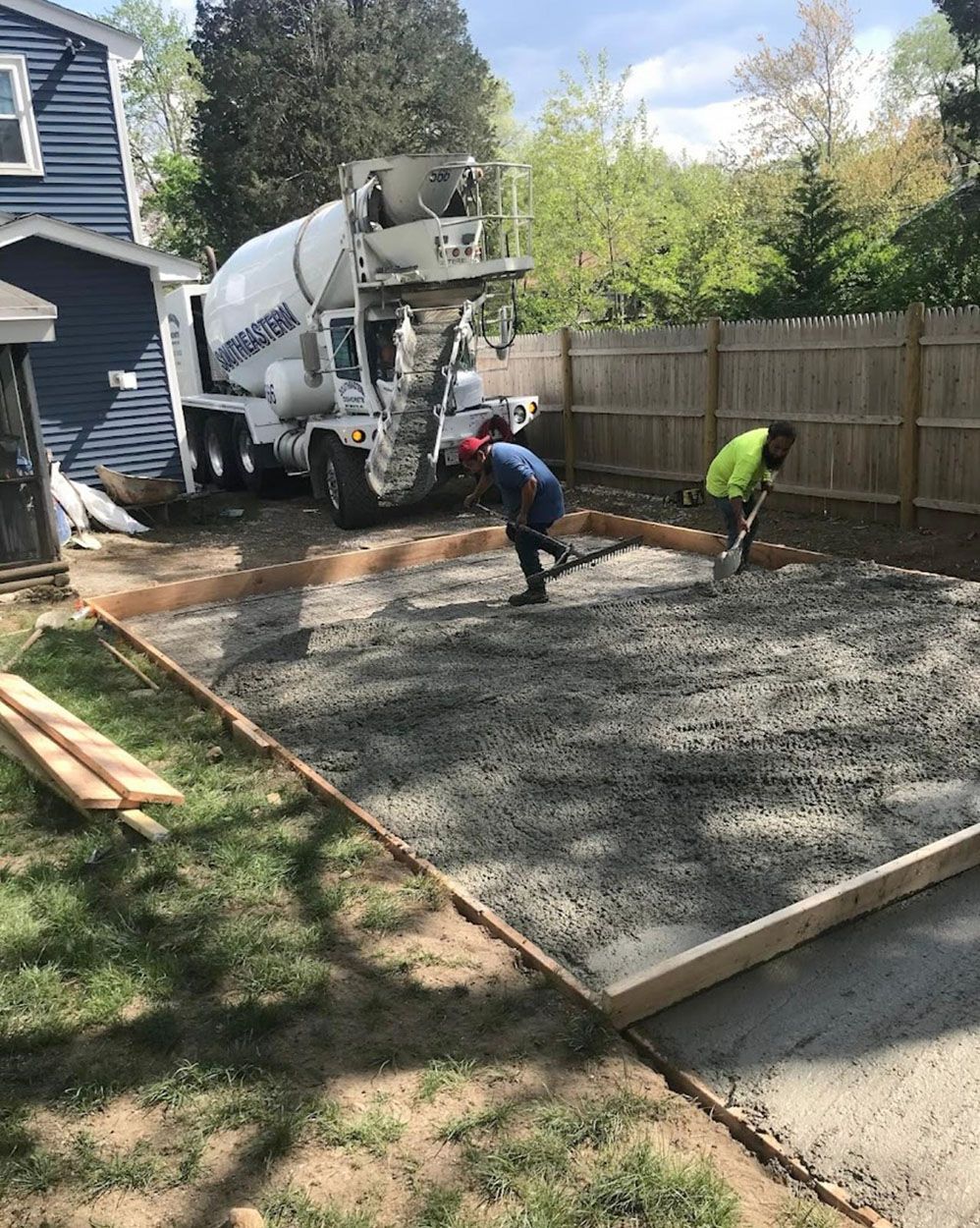 A concrete mixer truck is pouring concrete into a driveway