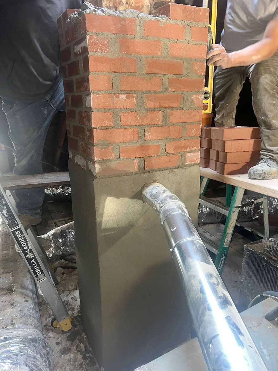 A man is laying bricks on top of a concrete chimney
