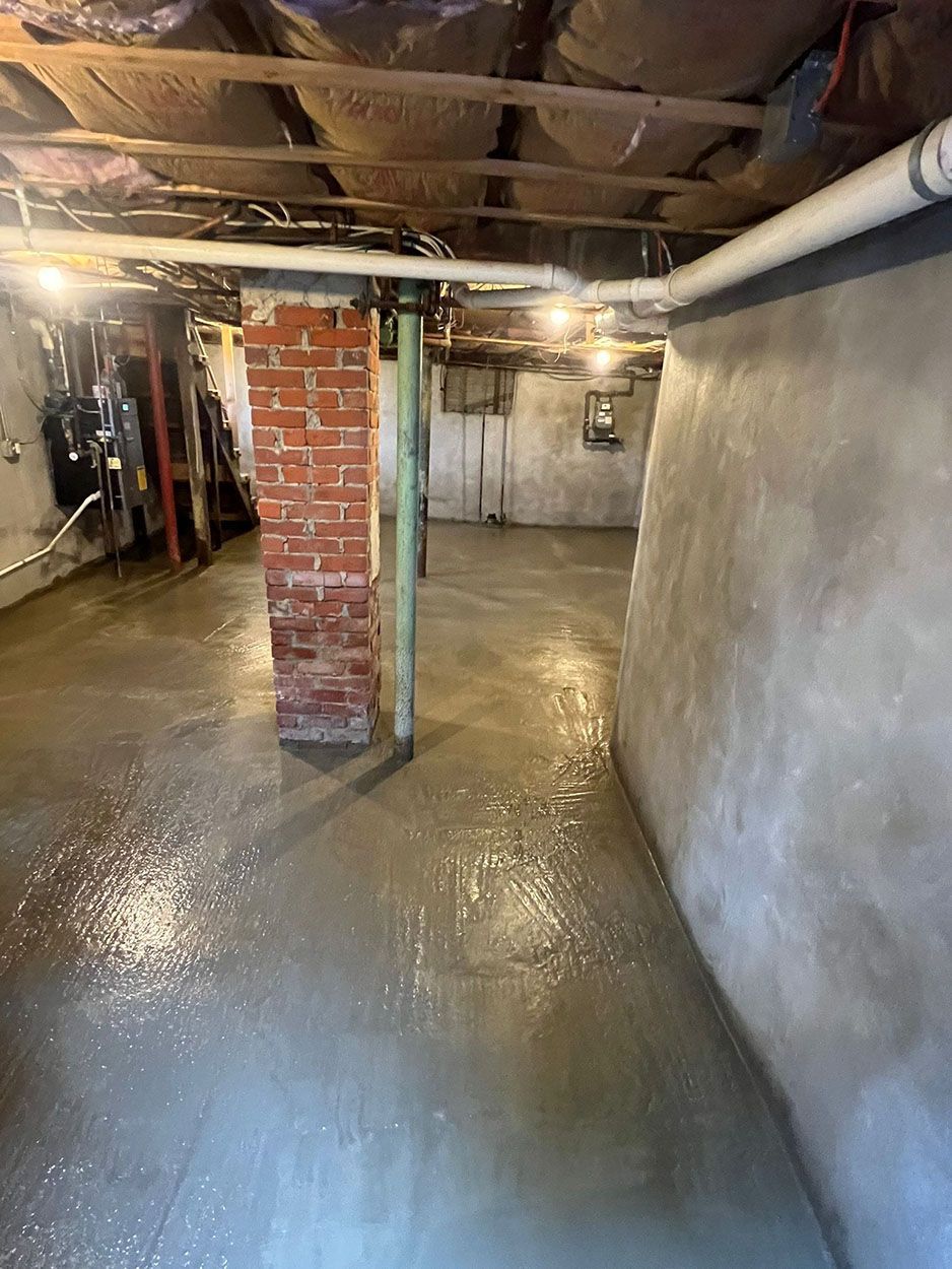 A basement with a brick chimney and a concrete floor