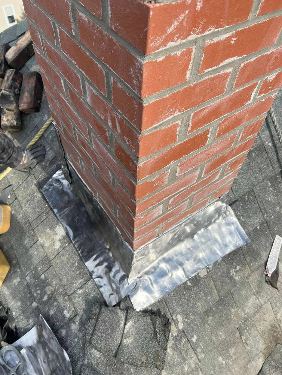A brick chimney is being repaired on a roof