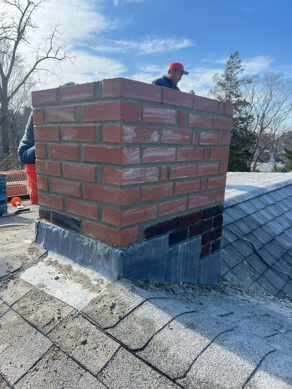 A brick chimney is being built on top of a roof